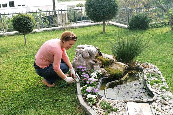 Jelena mentre pianta fiori accanto allo stagno